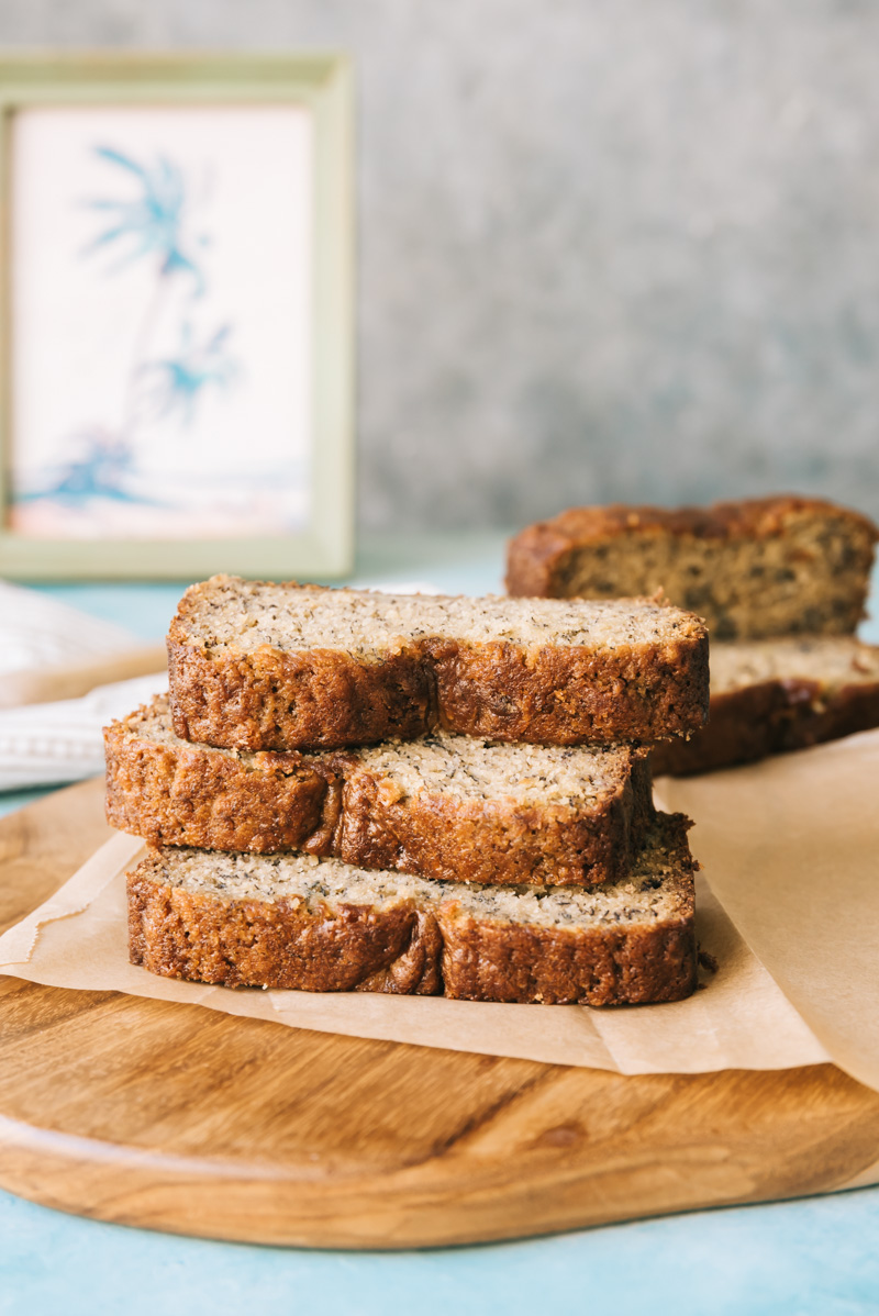 Banana bread slices stacked on a wood cutting board