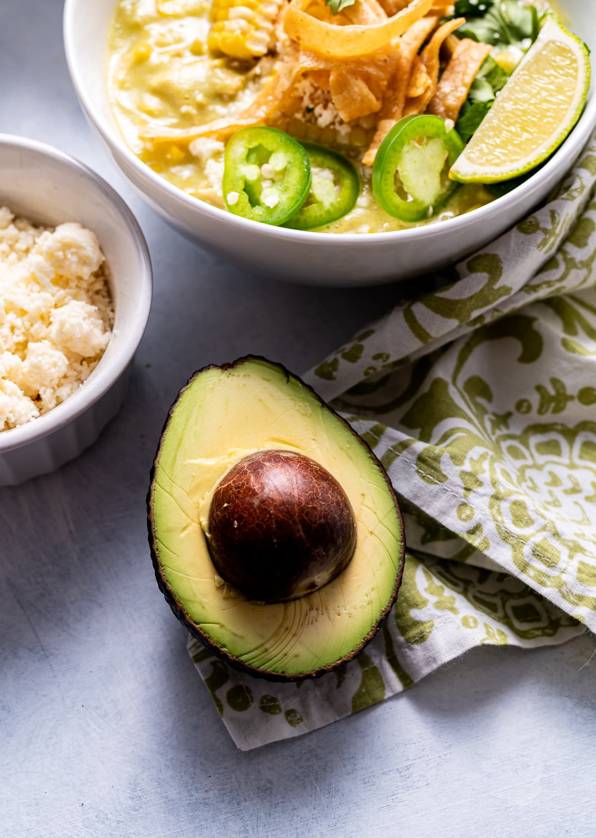 half of a cut avocado next to a bowl of chowder