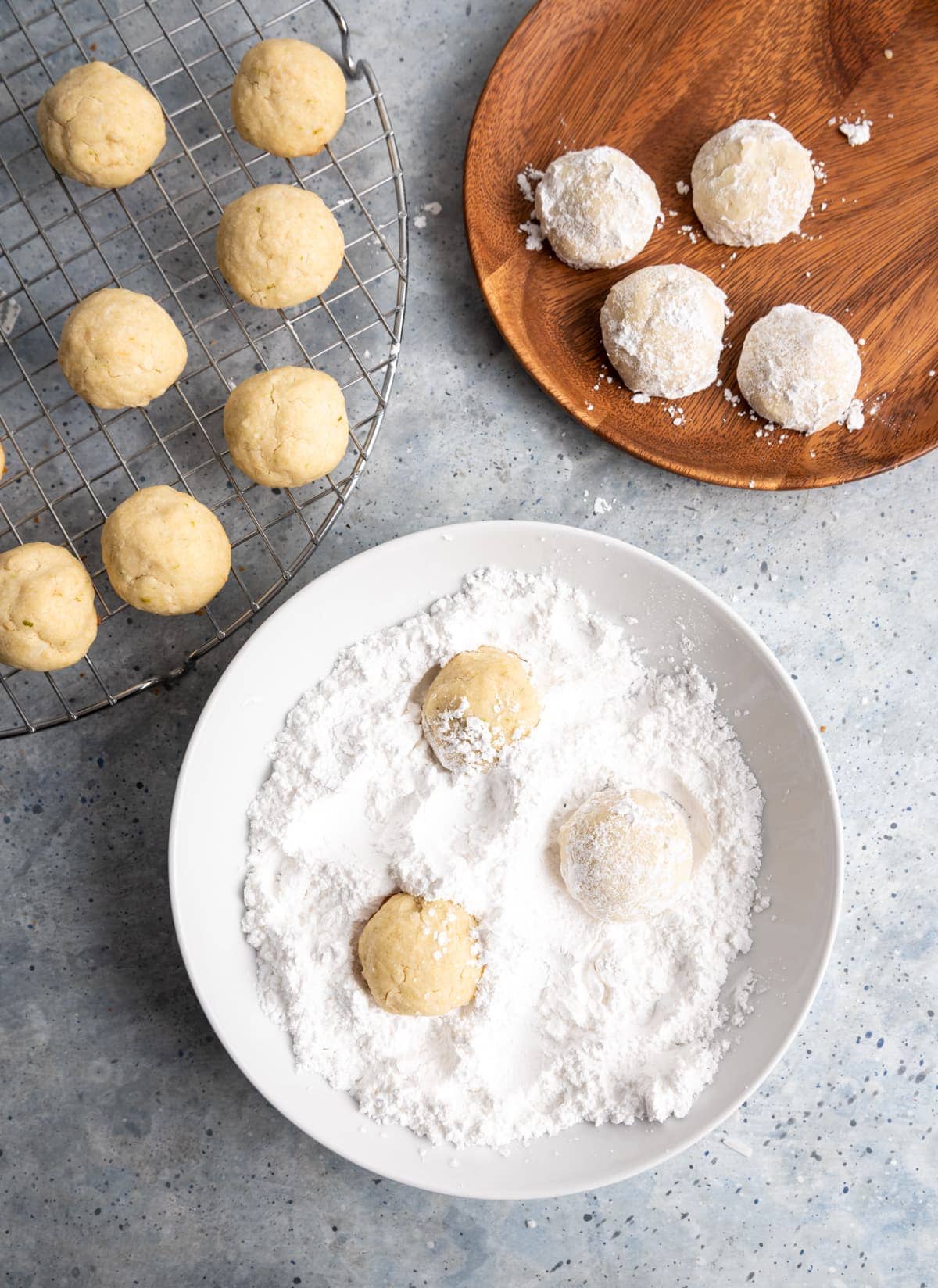 cookies on a wire cooling rack, cookies in a bowl with powdered sugar, cookies covered in powdered sugar on a wooden plate