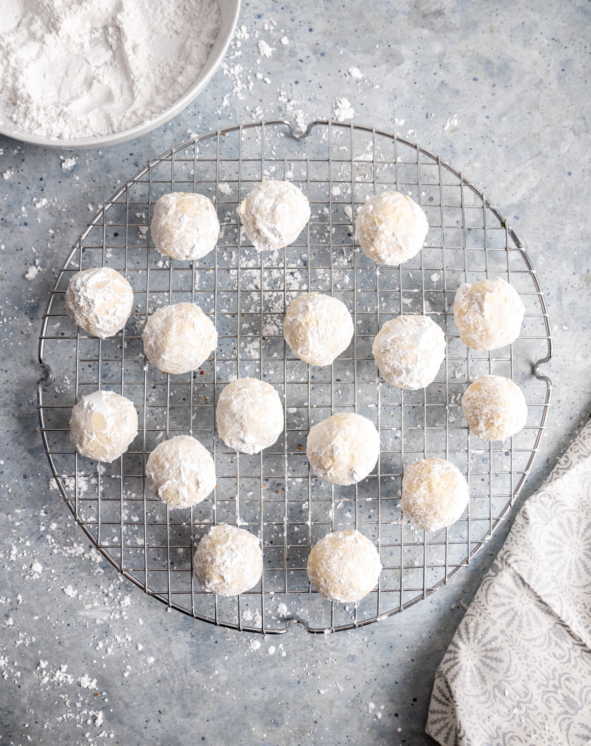 round cookies covered in powdered sugar on a round wire cooling rack