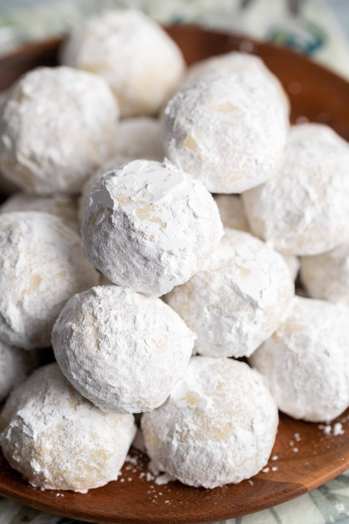 small round cookies covered in powdered sugar on a brown plate