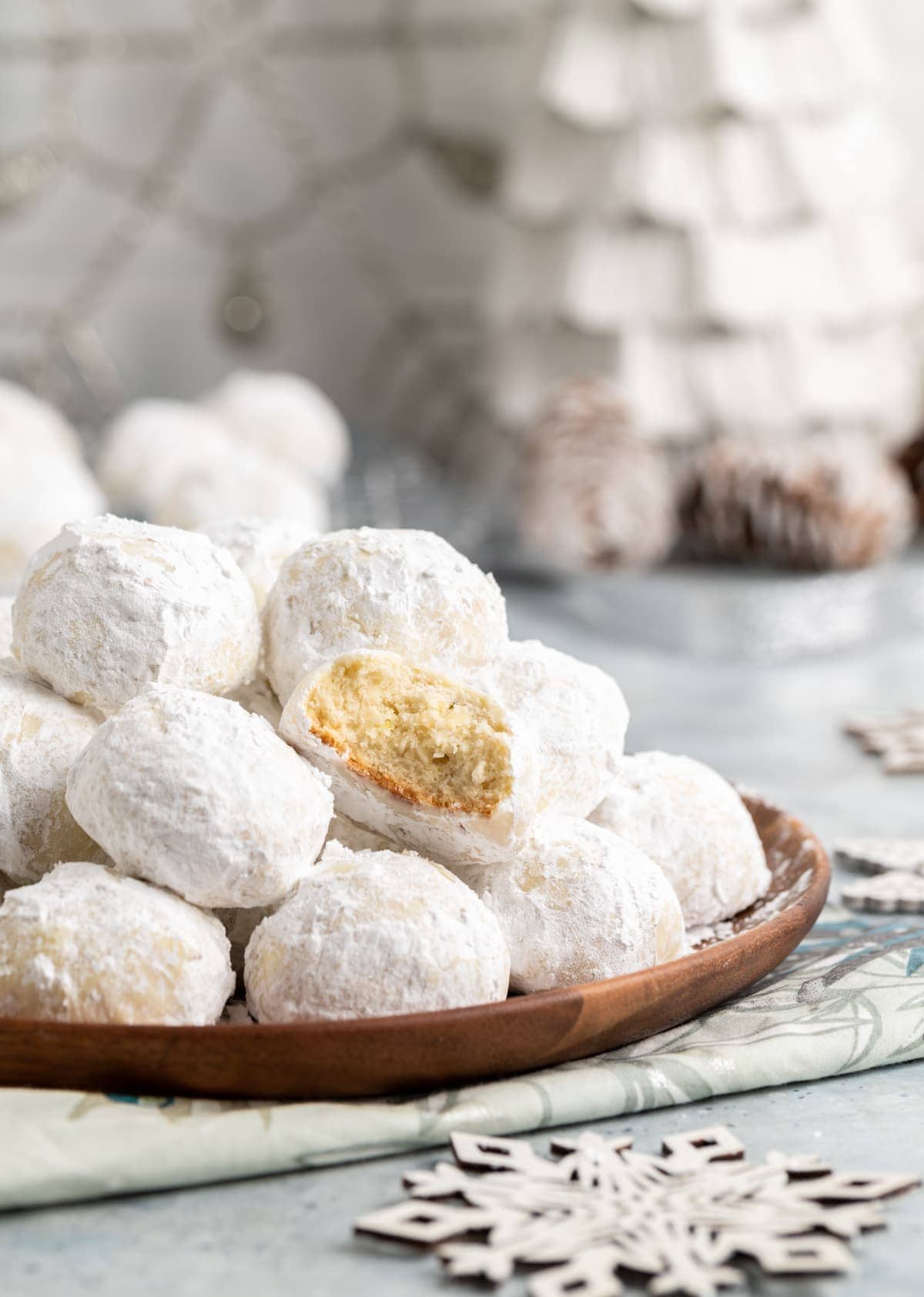 small round cookies covered in powdered sugar on a brown plate