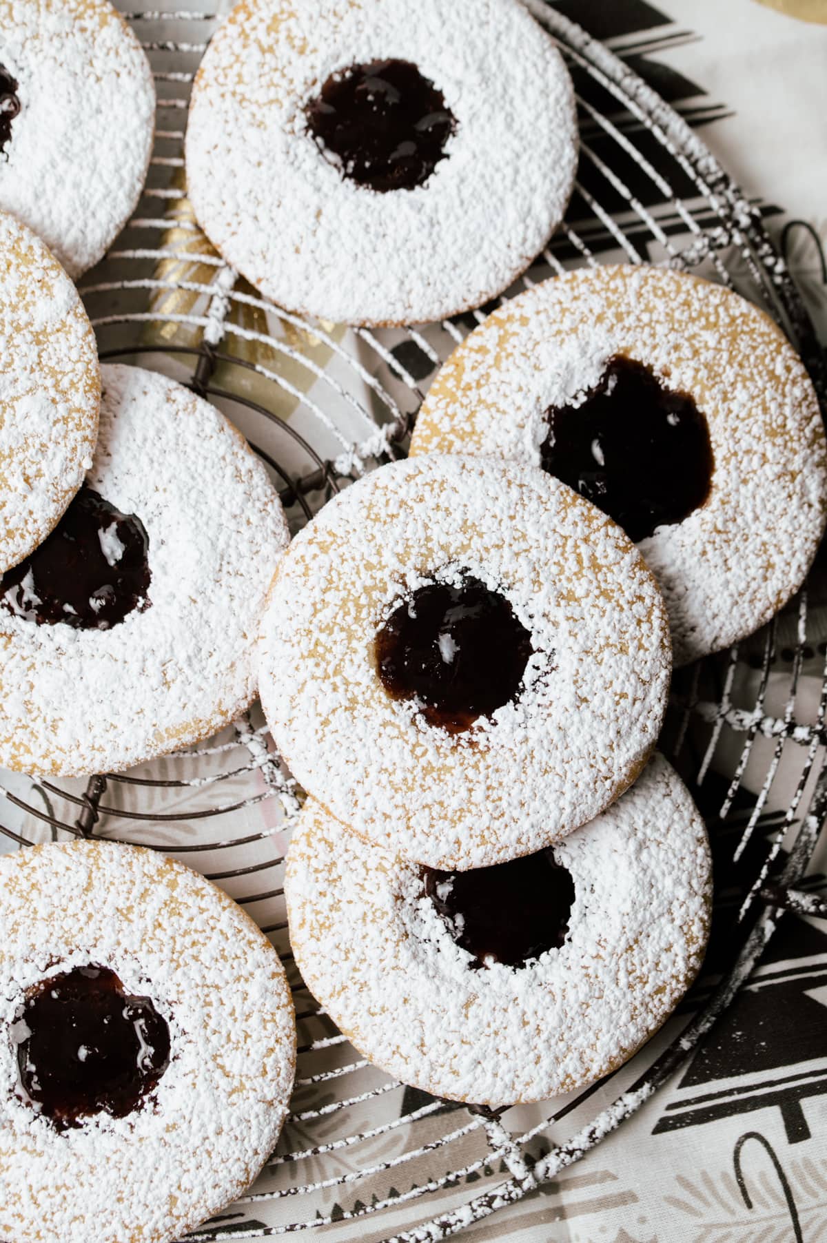 round sandwich cookies with dark purple jam layered on a wire rack