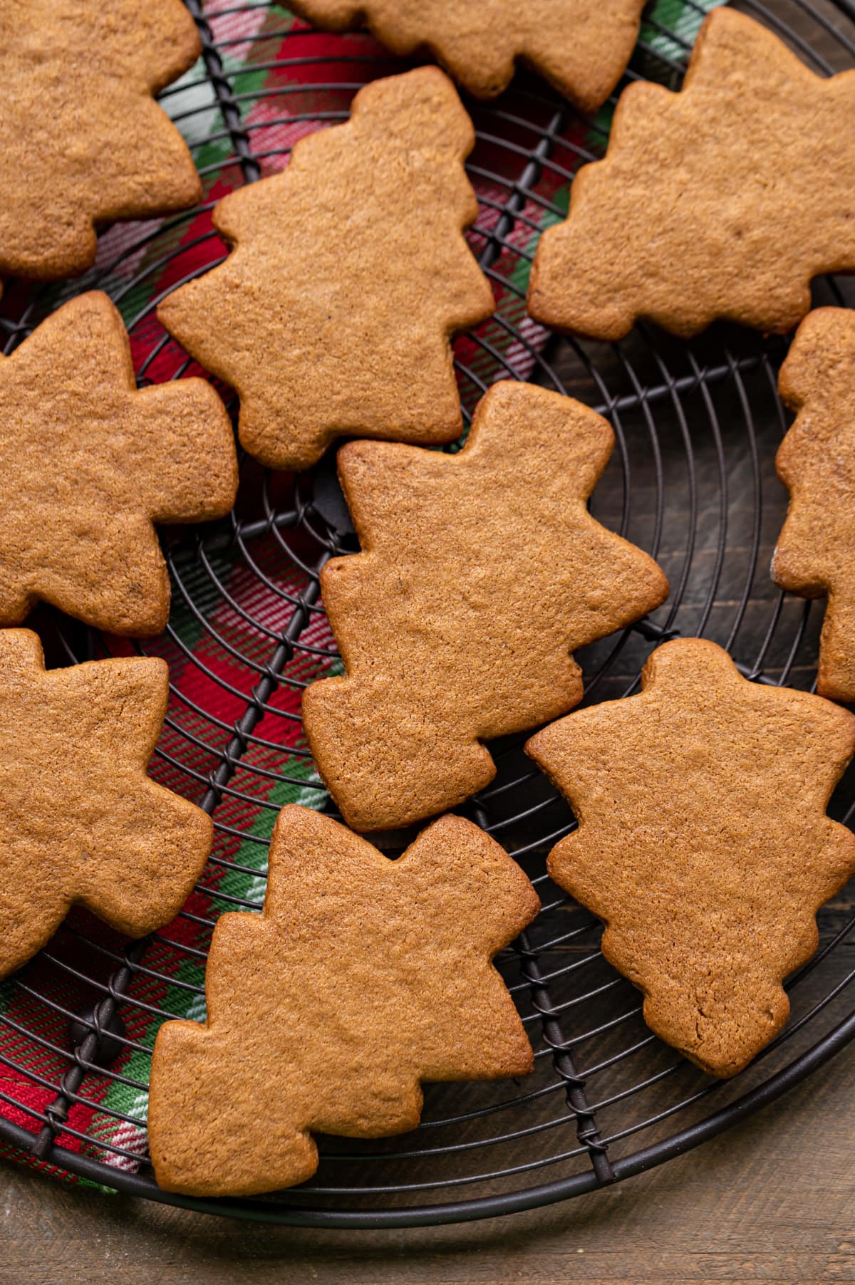 baked gingerbread christmas tree cookies on a round wire cooling rack