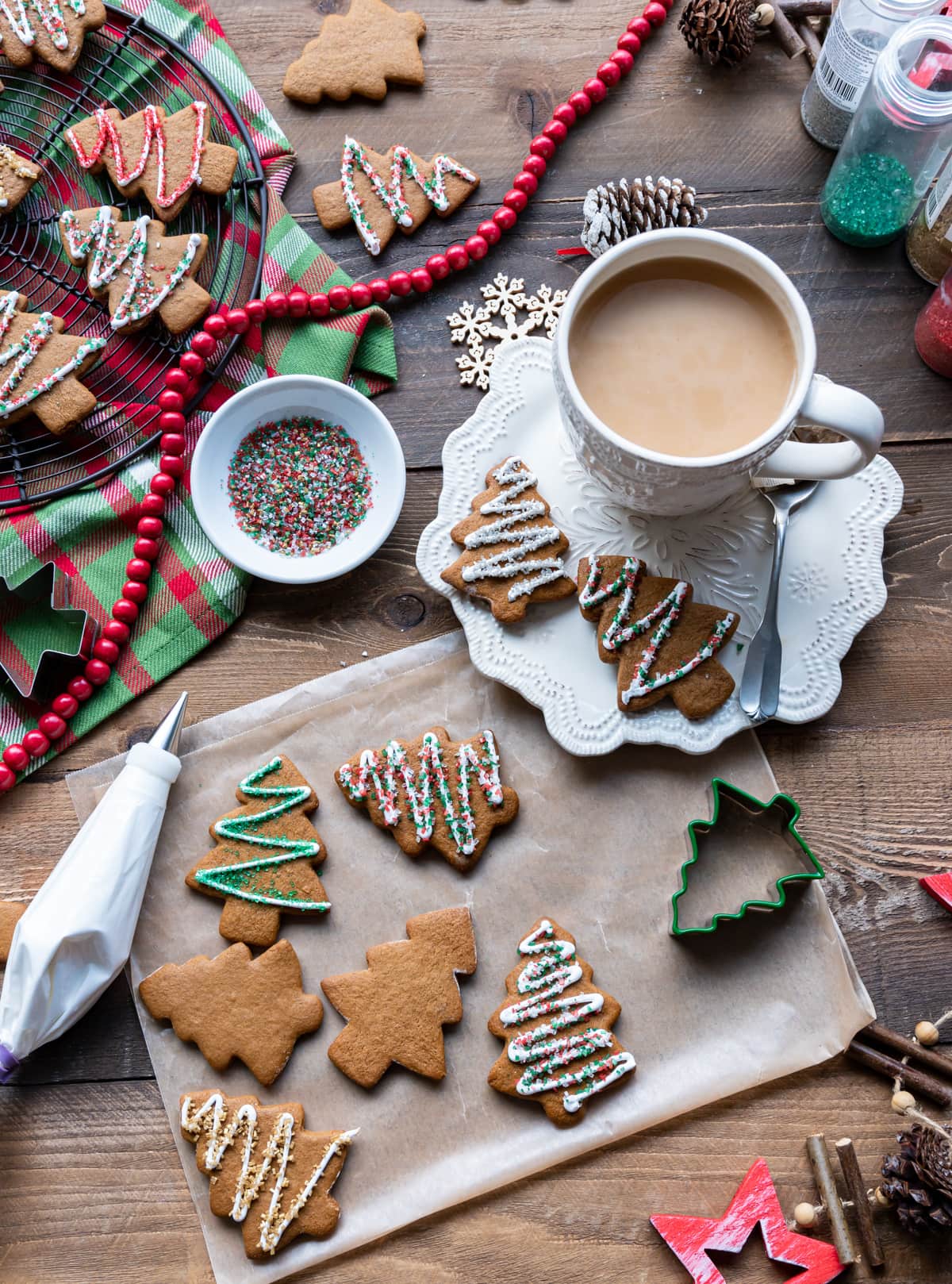 gingerbread christmas tree cut out cookies, cup of tea, cookie cutters, bowl of colored sugar