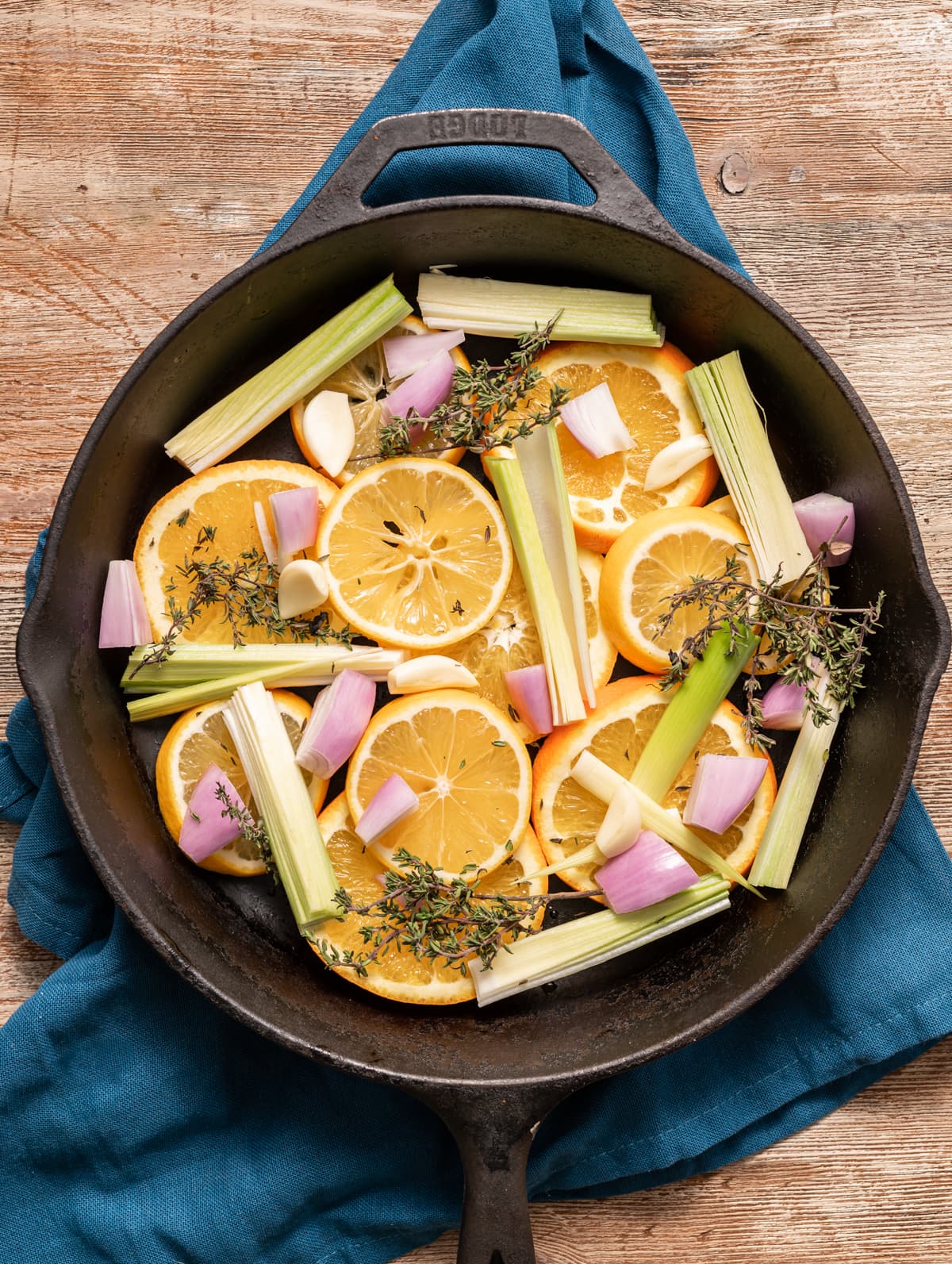 cast iron skillet filled with sliced oranges lemons leeks shallots garlic and thyme