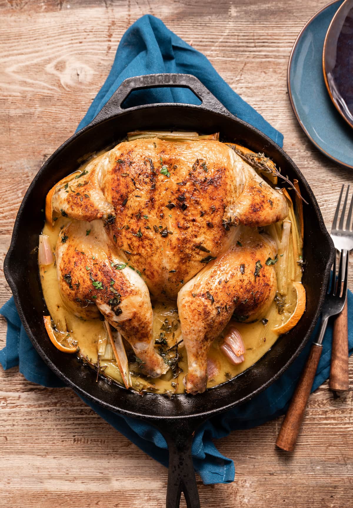 whole roasted chicken in a skillet with lemons and oranges and leeks