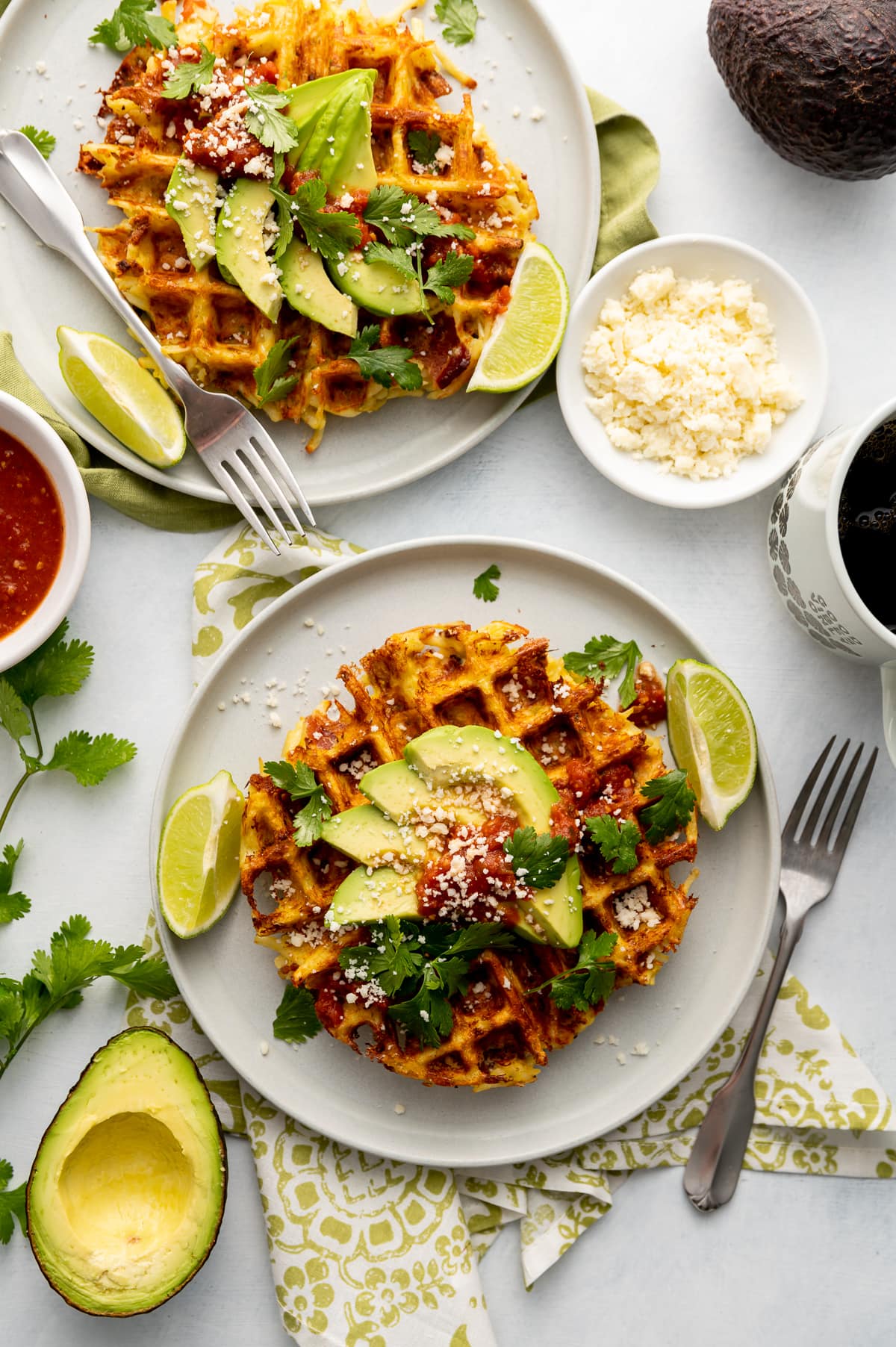 savory hash brown waffles with avocado slices lime slices whole and half avocados on white plates