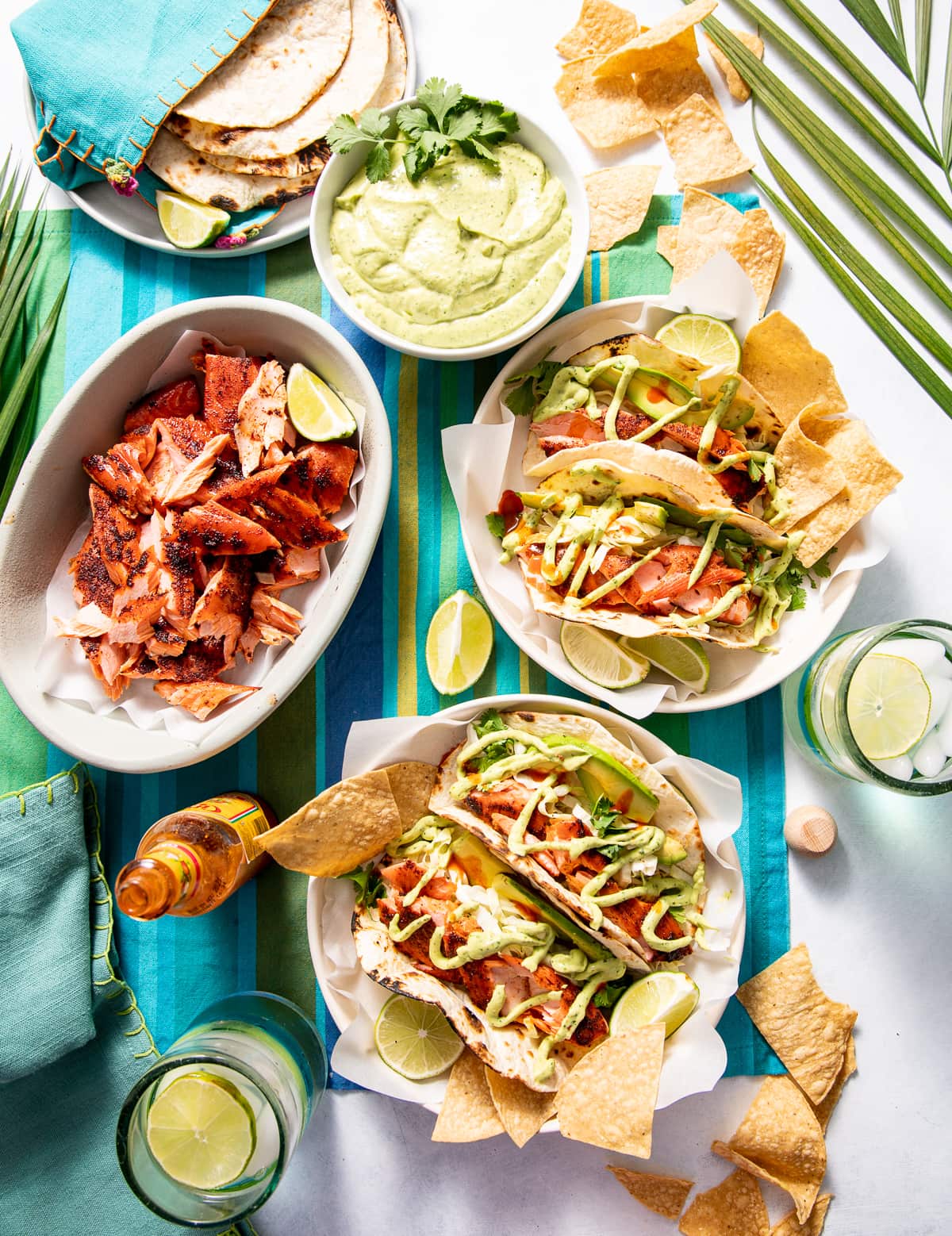 smoked salmon tacos in white bowls with chips smoked salmon a bowl green avocado crema in a white bowl plate of tortillas