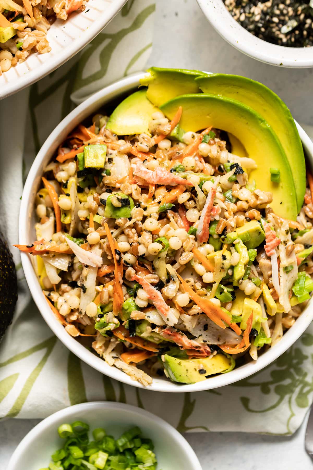 california roll salad with mixed grains and vegetables in white bowls bowl or green onion whole avocado bowl of seaweed seasoning