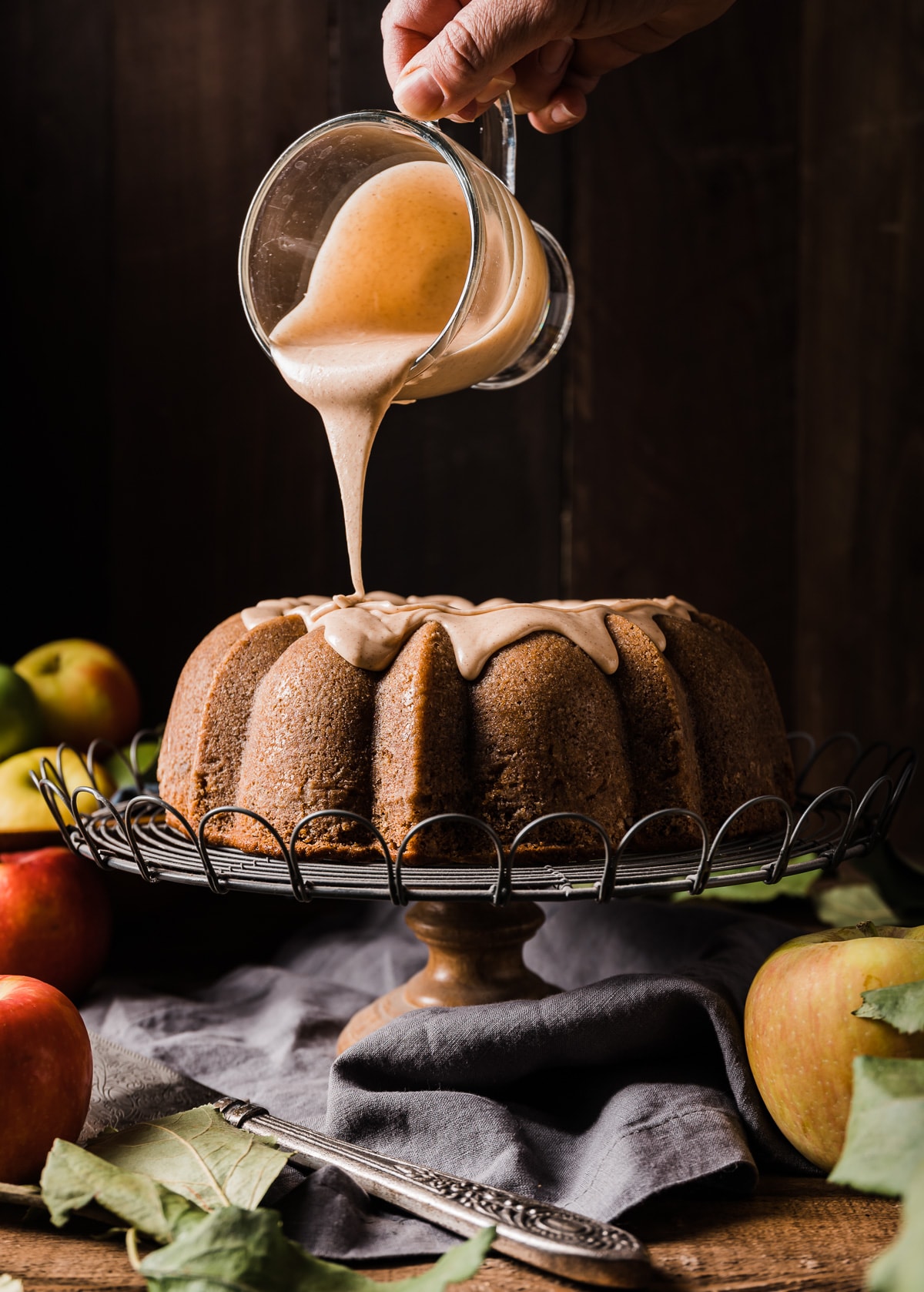 icing being poured onto a bundt cake on a wire cake stand