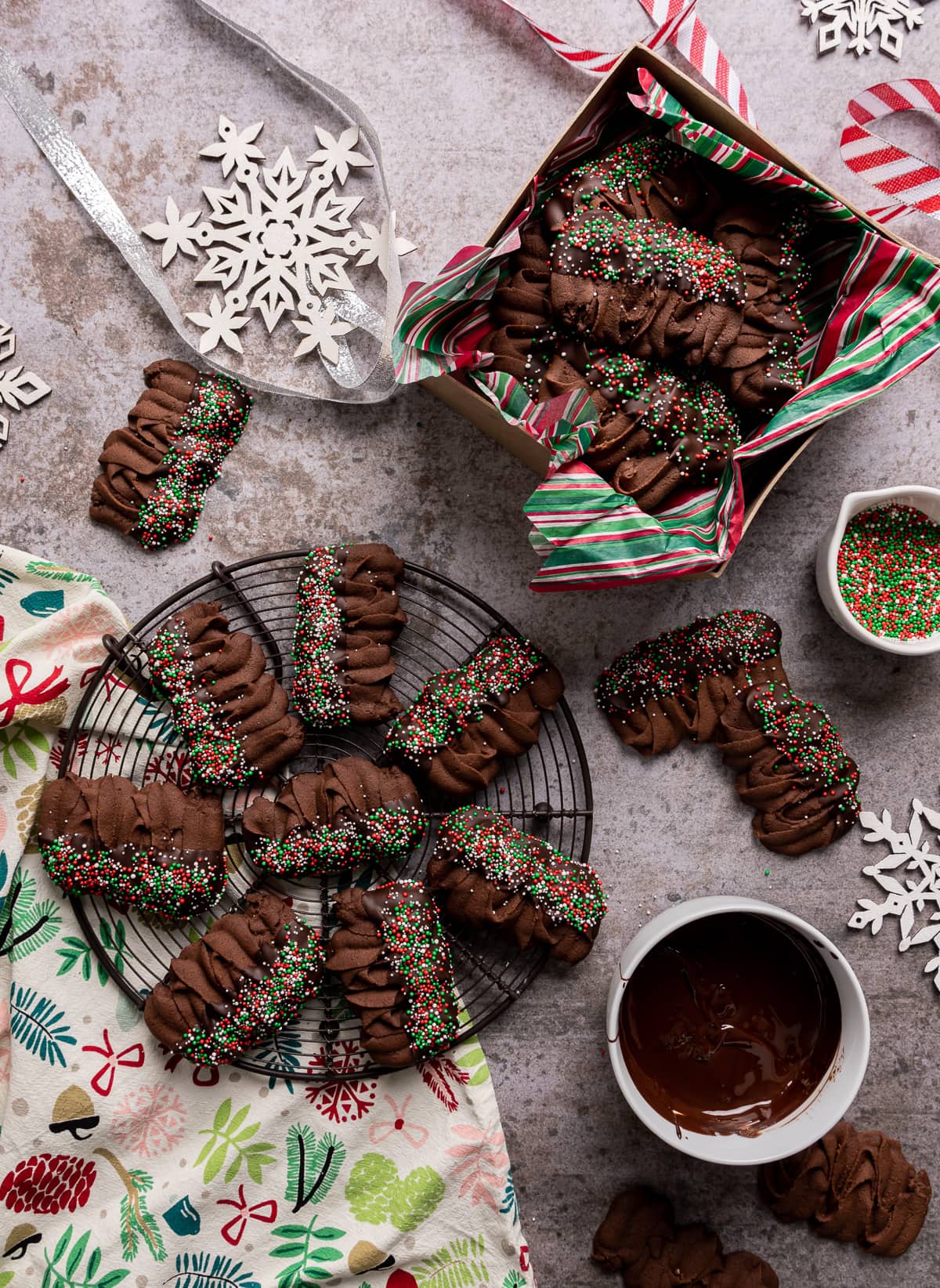 chocolate viennese butter cookies half dipped in chocolate with red green and white sprinkles on wire rack and some in a box with red white and green paper viennese whirls