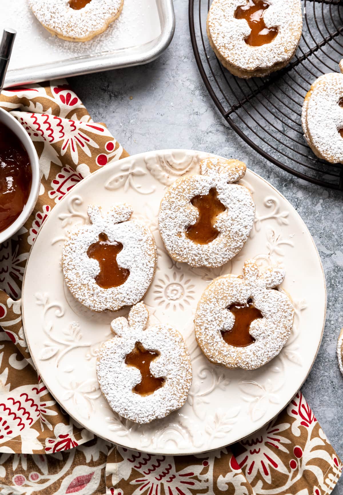 apple shaped linzer cookies with brown apple jam filling on white plate