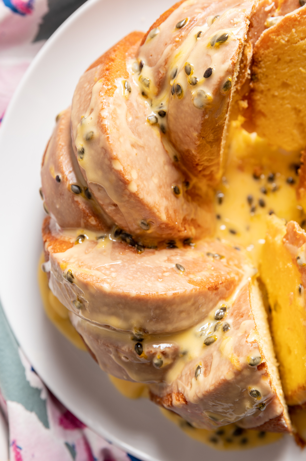 yellow passionfruit bundt cake sliced on a large white plate 