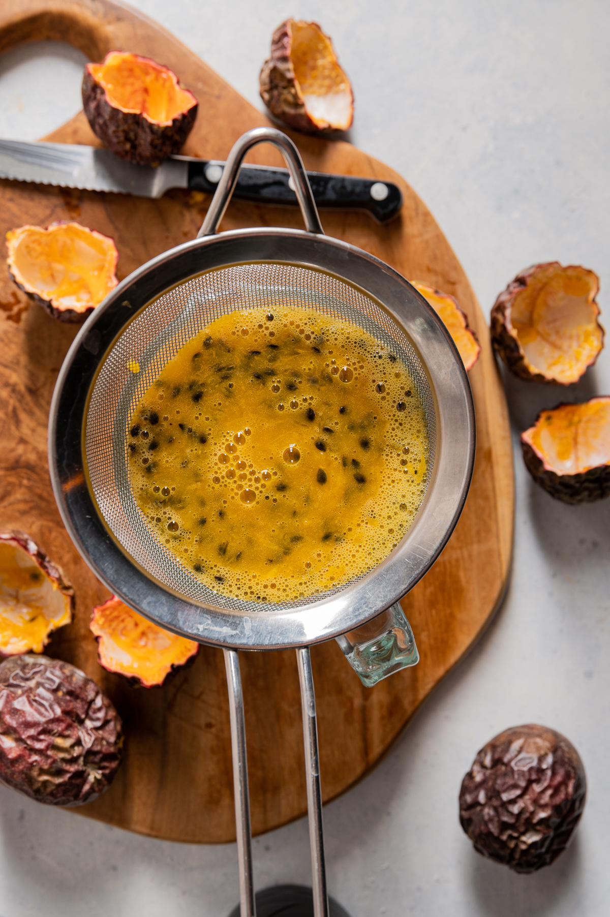 passion fruit juice being strained into a measuring cup