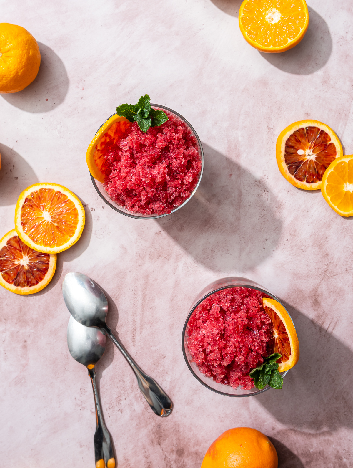 reddish orange blood orange granita in glasses spoons blood orange and tangerine slices