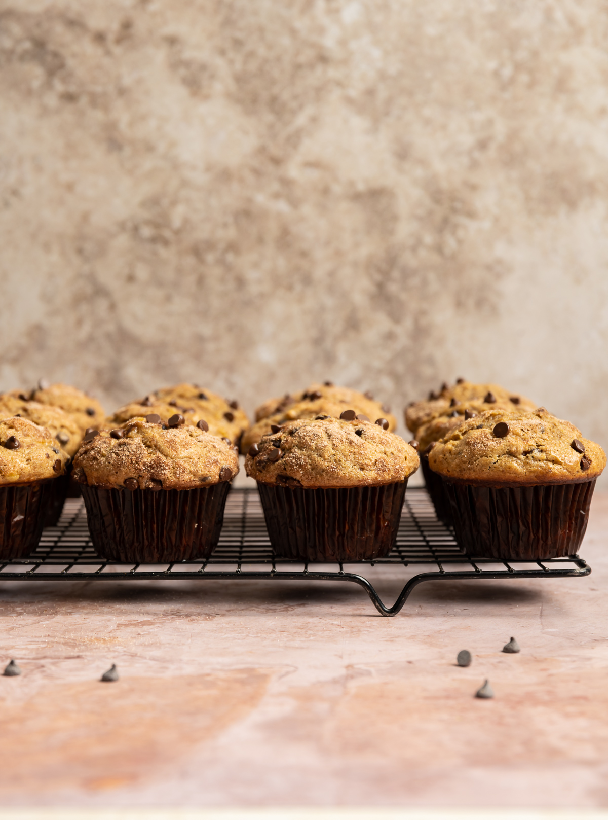 muffins with chocolate chips in brown wrappers on a wire cooling rack