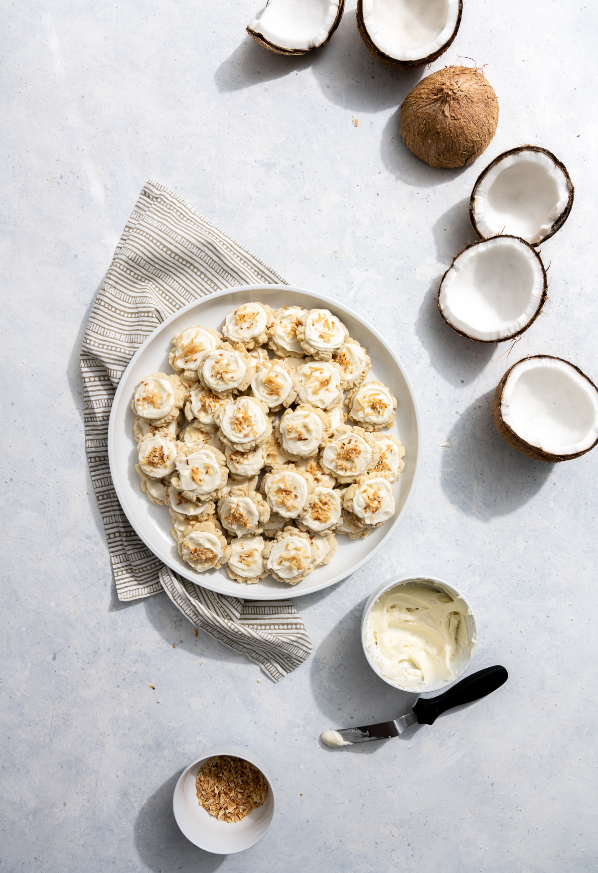 coconut cookies with coconut frosting on a white plate fresh coconuts broken into pieces