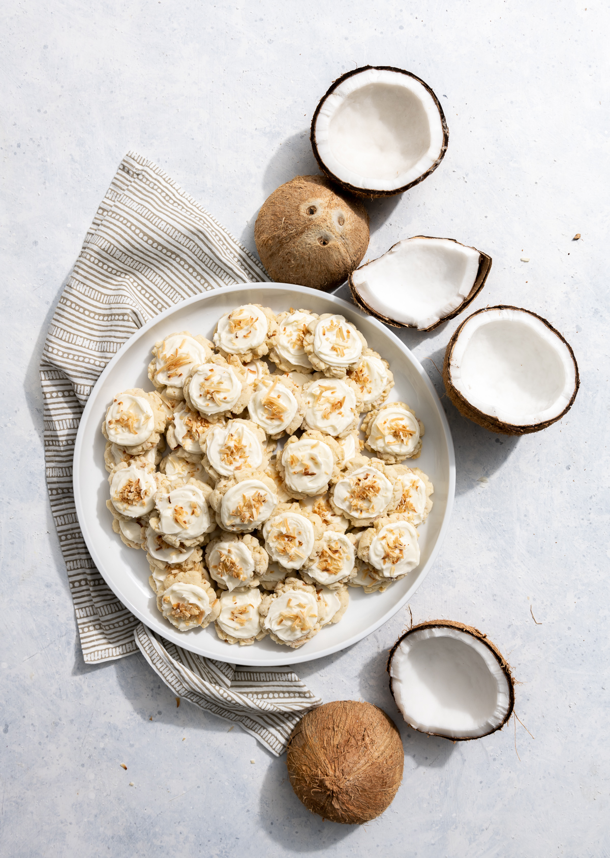 coconut cookies with coconut frosting on a white plate fresh coconuts broken into pieces