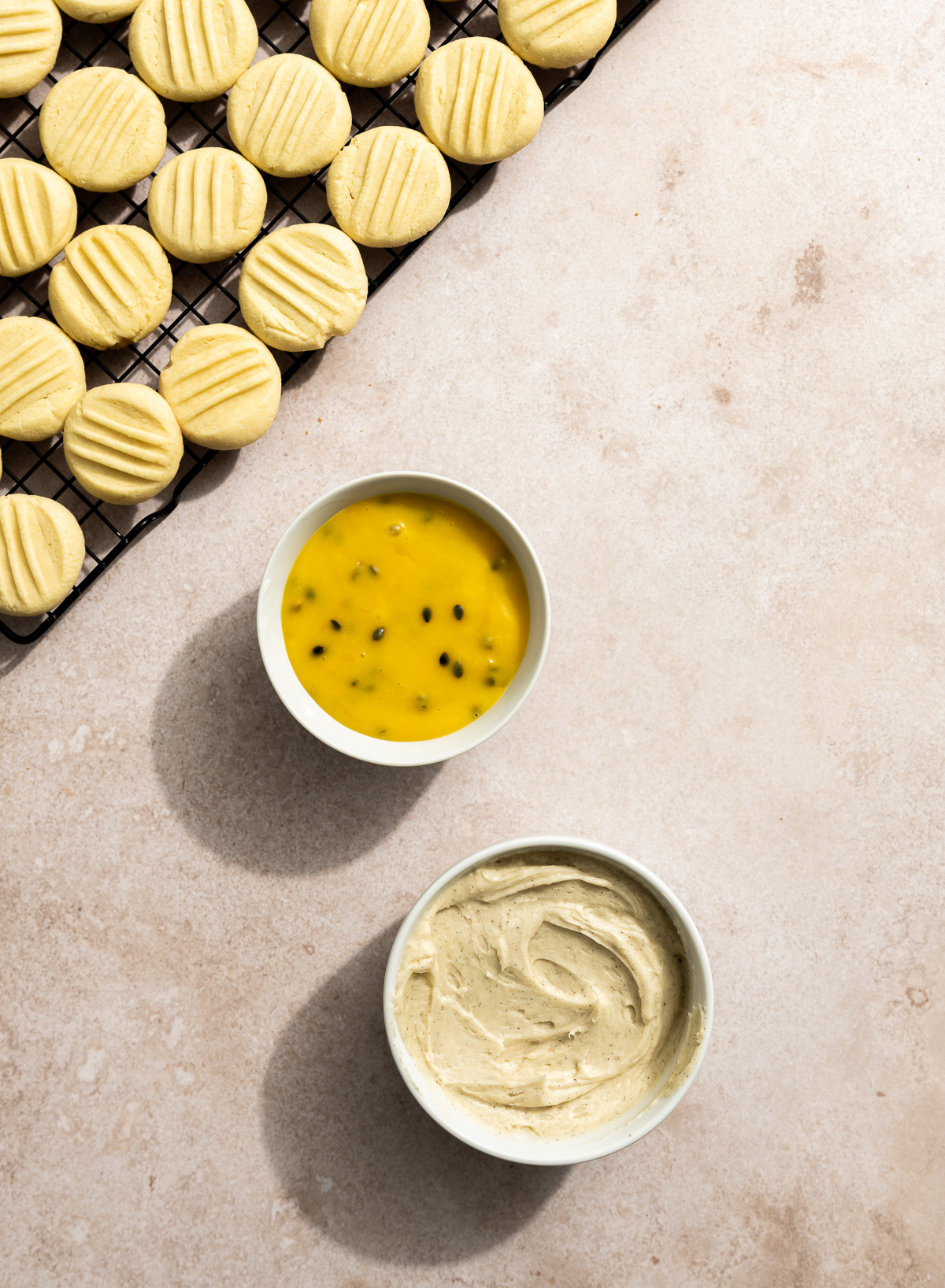 round butter cookies on a cooling rack bowl or passionfruit curd bowl of vanilla buttercream