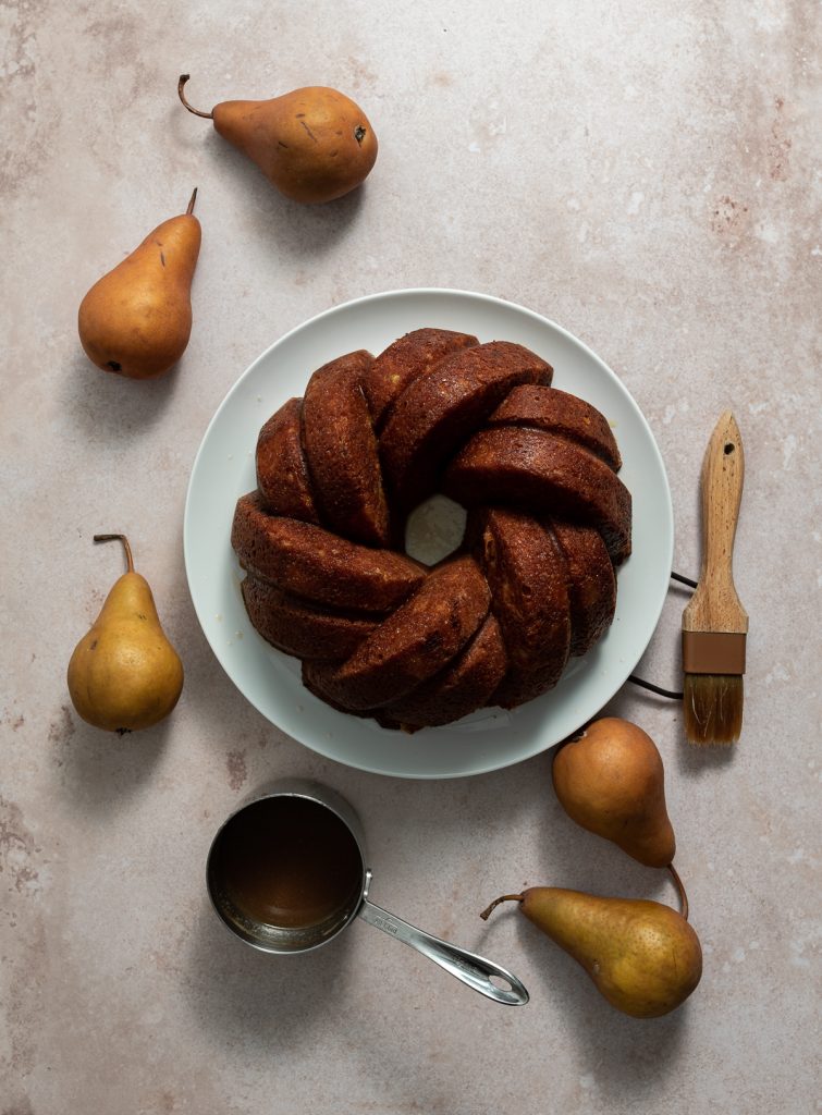 baked bundt cake in pan whole pears pastry brush cup of maple glaze