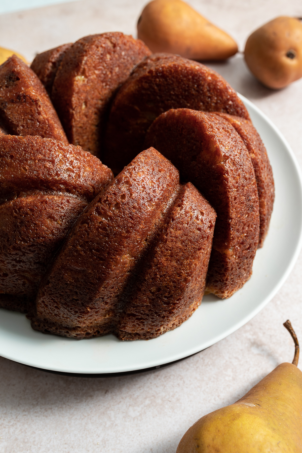 maple pear bundt cake on white plate with whole bosc pears slice 