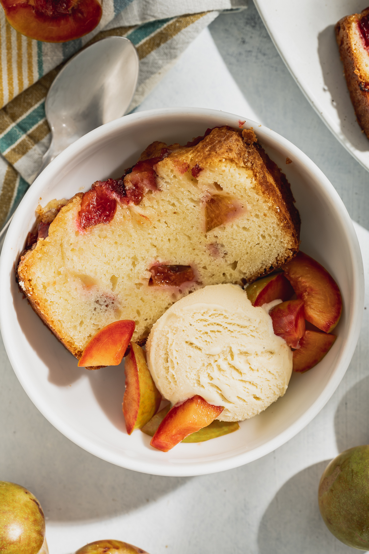 slice of pound cake with plums and scoop of vanilla ice cream in a bowl