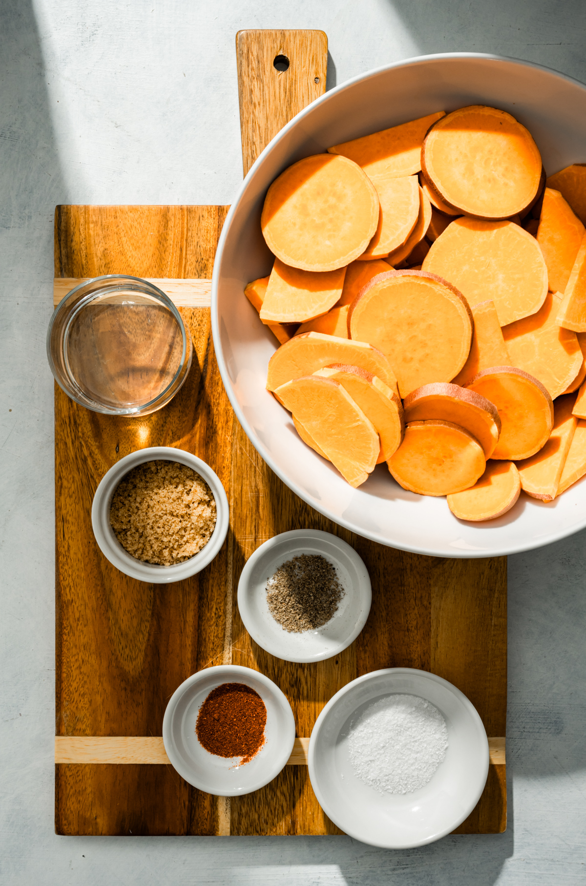 sliced sweet potatoes in a bowl bowls of spices and sugar bowl of coconut oil