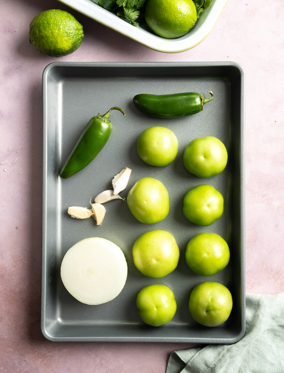 tray with raw whole tomatillos white onion garlic cloves jalapeños