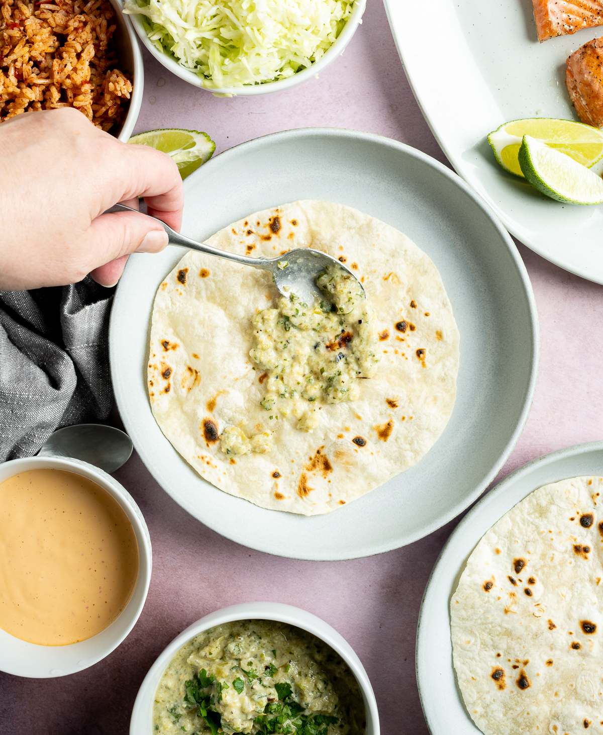 green salsa being spread over a tortilla on a light blue plate