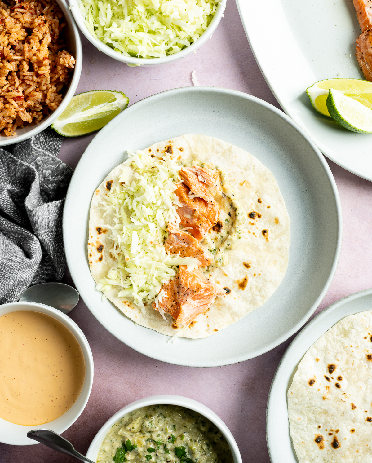 salmon green salsa and green shredded cabbage on a tortilla on a light blue plate