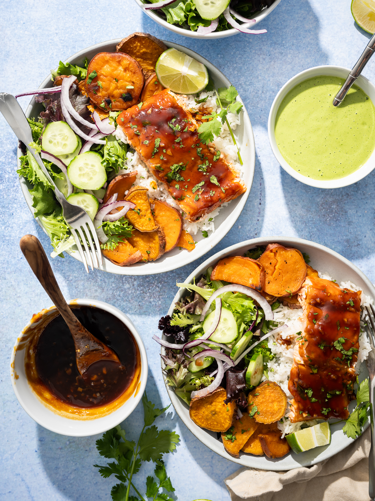 salmon fillets in bowls with sweet potato slices salad lime sliced bowl of green dressing bowl of hot honey sauce