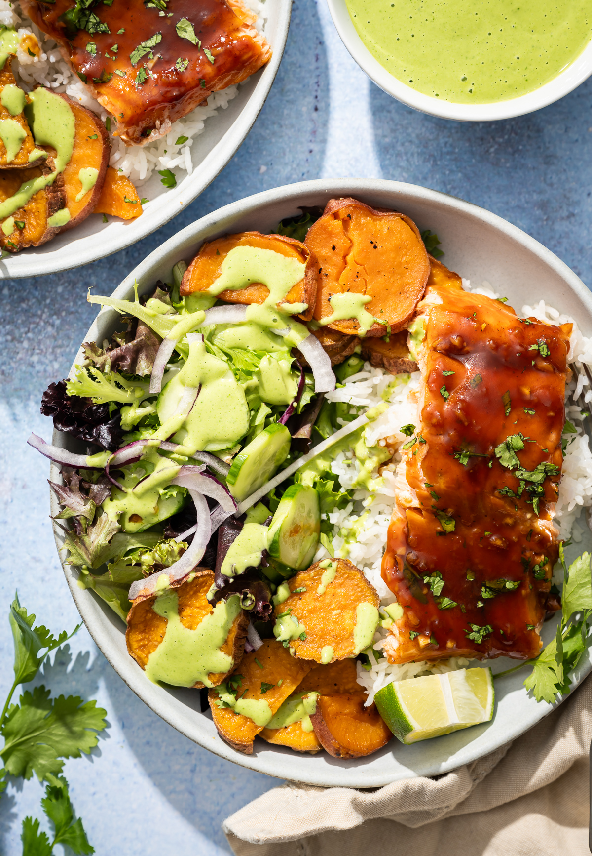 salmon fillets in bowls with sweet potato slices salad lime sliced bowl of green dressing 