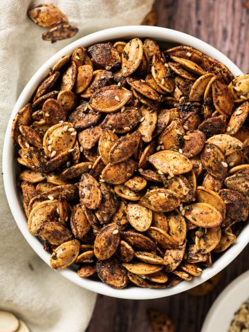 brown roasted pumpkin seeds in white bowl