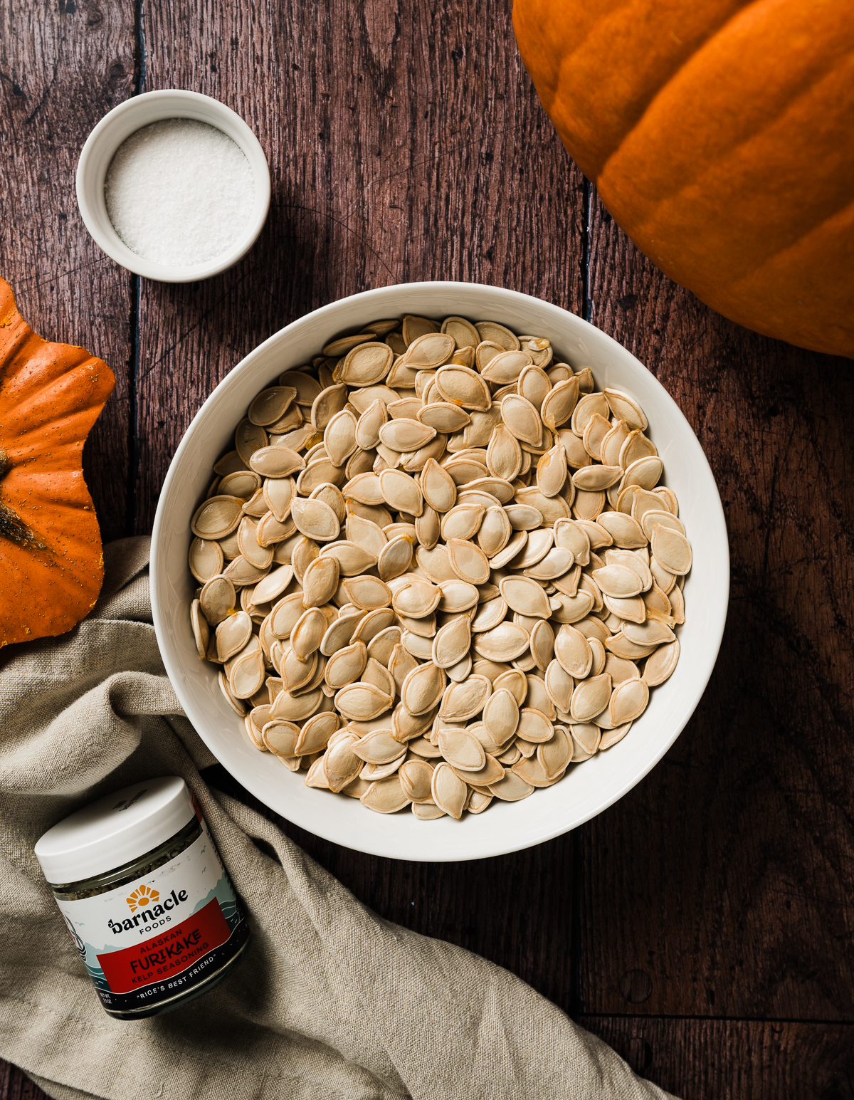 raw pumpkin seeds in white bowl
bowl of salt jar of furikake seasoning