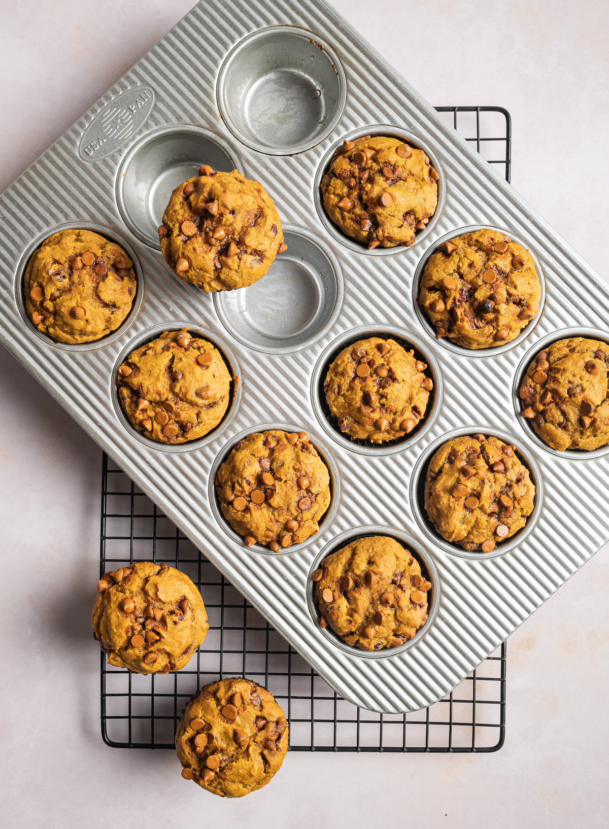 pumpkin muffins in a muffin tin a two on a wire cooling rack