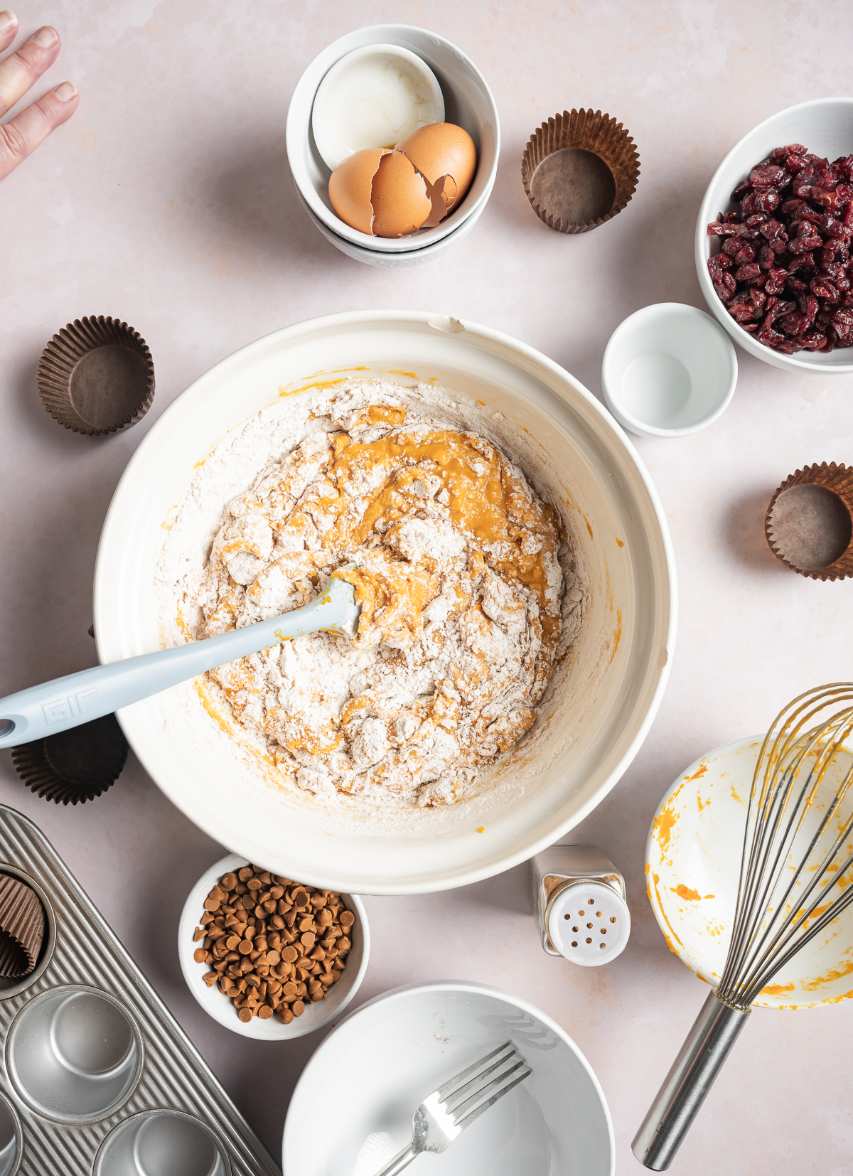 flour added to pumpkin muffin batter muffin in a bowl, various bowls of separate muffin ingredients