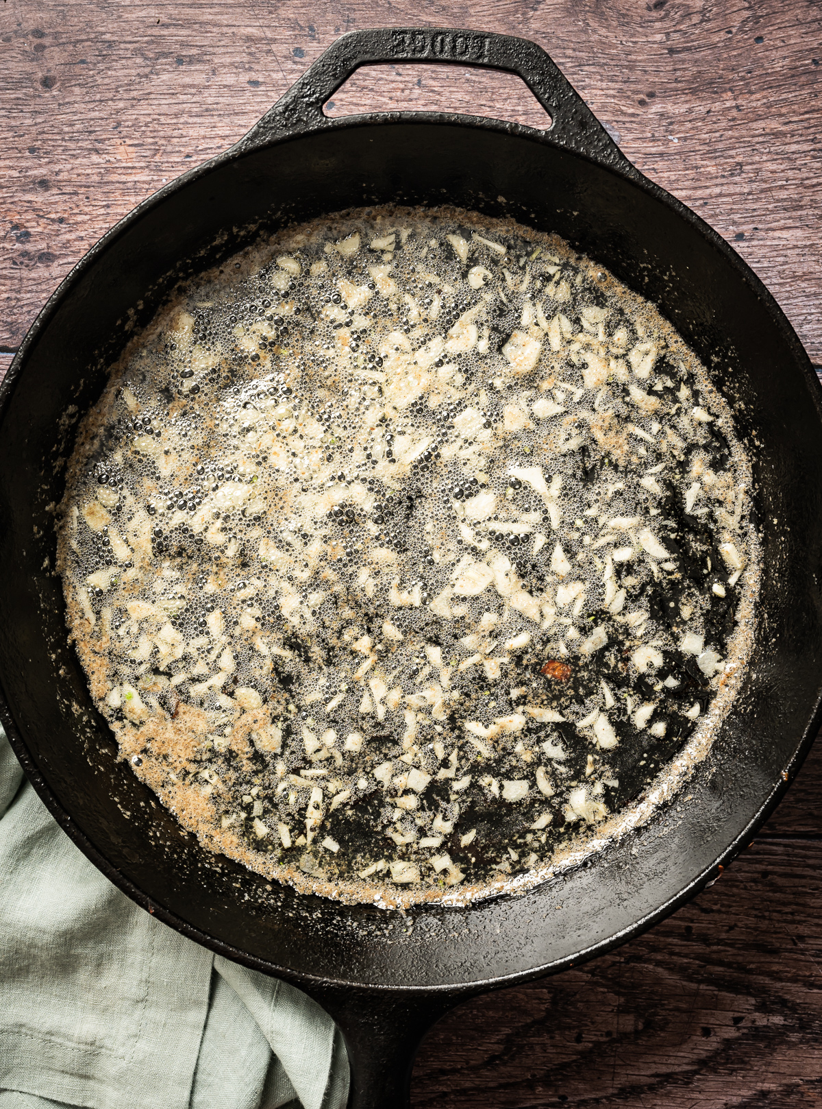 thinly sliced garlic with melted butter in cast iron pan