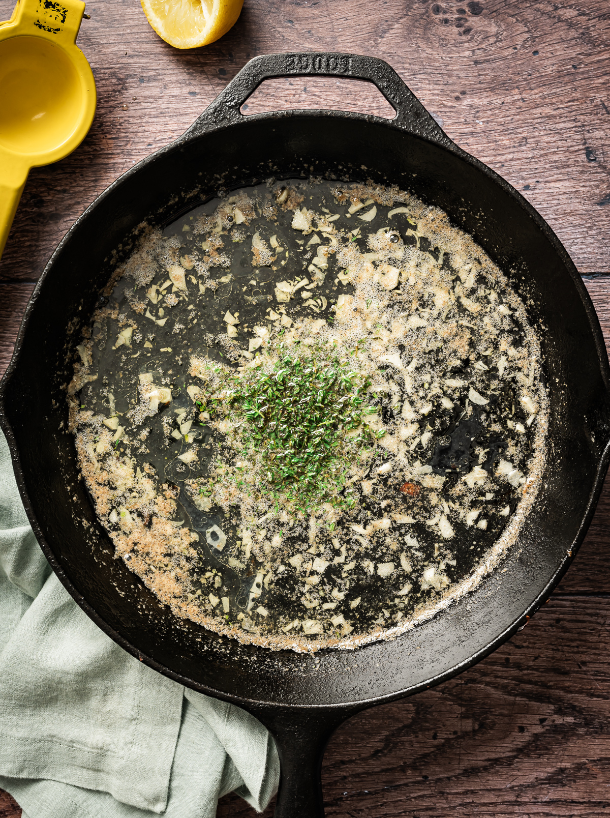 chopped fresh thyme with sliced garlic and melted butter in cast iron pan