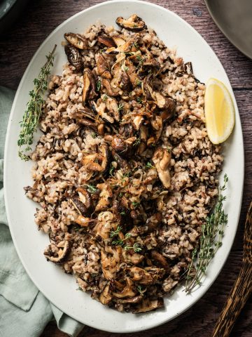 large platter with wild rice and sauteed mushrooms lemon wedge fresh thyme