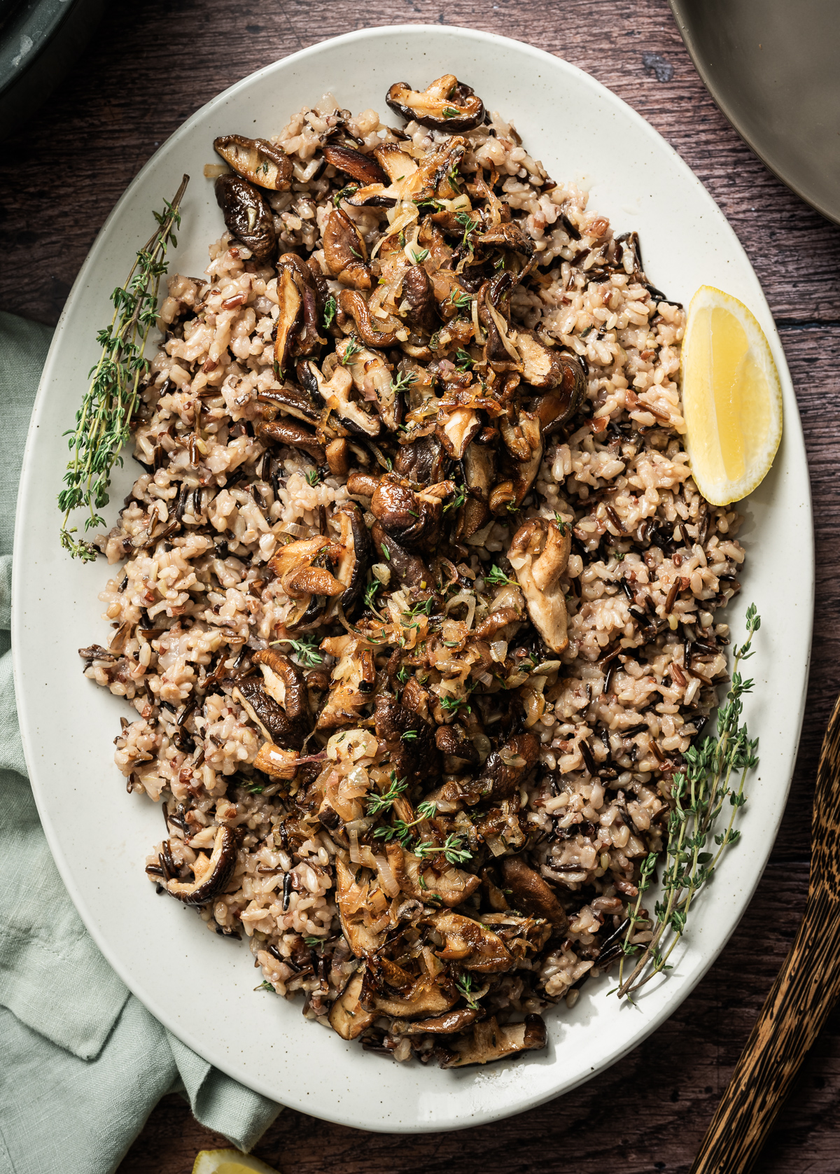 large platter with wild rice and sauteed mushrooms lemon wedge fresh thyme