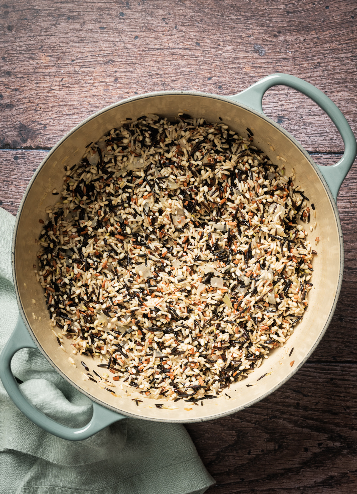 large cast iron enamel pan with sauteed onion and wild rice