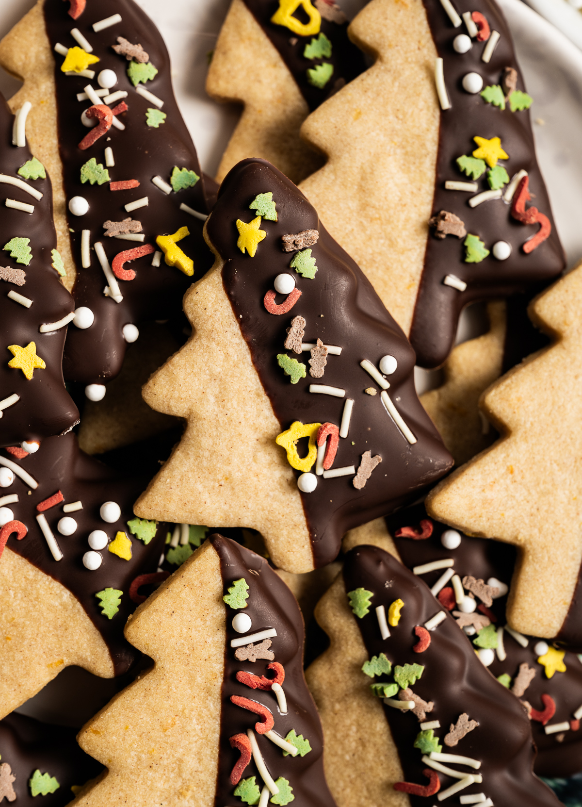 tree shaped cinnamon shortbread cookies half dipped in chocolate with sprinkles