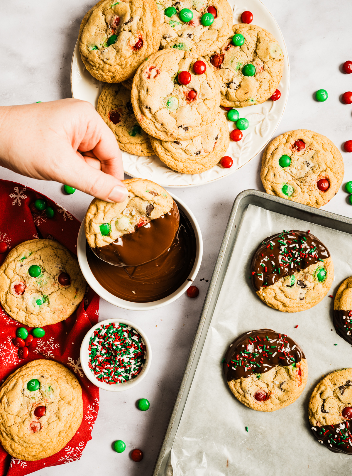 red and green M&M chewy chocolate chip cookies half dipped in chocolate decorated with red white and green sprinkles