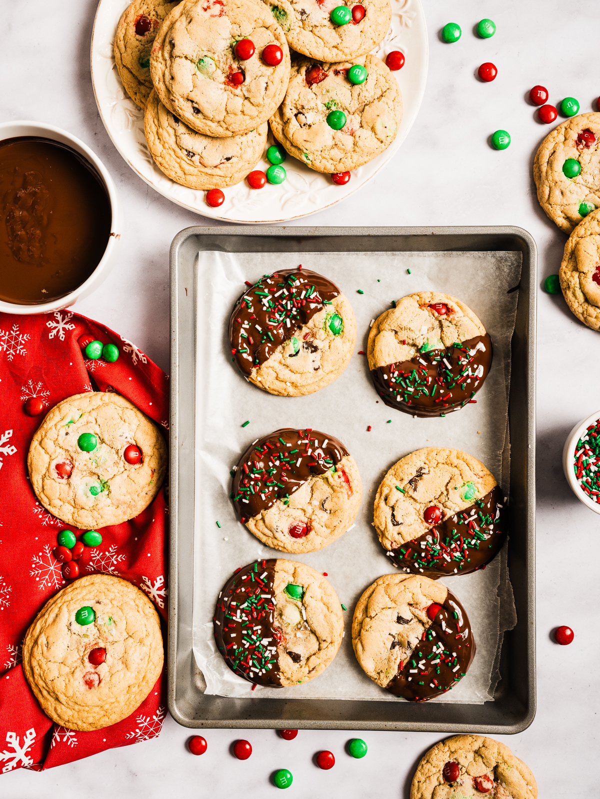 red and green M&M chewy chocolate chip cookies half dipped in chocolate decorated with red white and green sprinkles