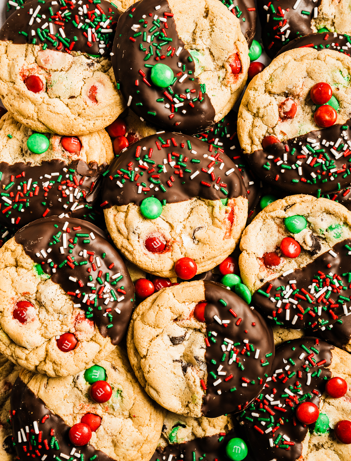 red and green M&M chewy chocolate chip cookies half dipped in chocolate decorated with red white and green sprinkles