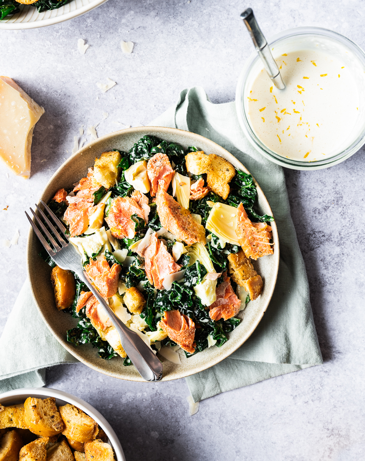 Salmon Caesar salads in bowls chunk of Parmesan cheese Meyer lemon jar of Meyer lemon Caesar dressing