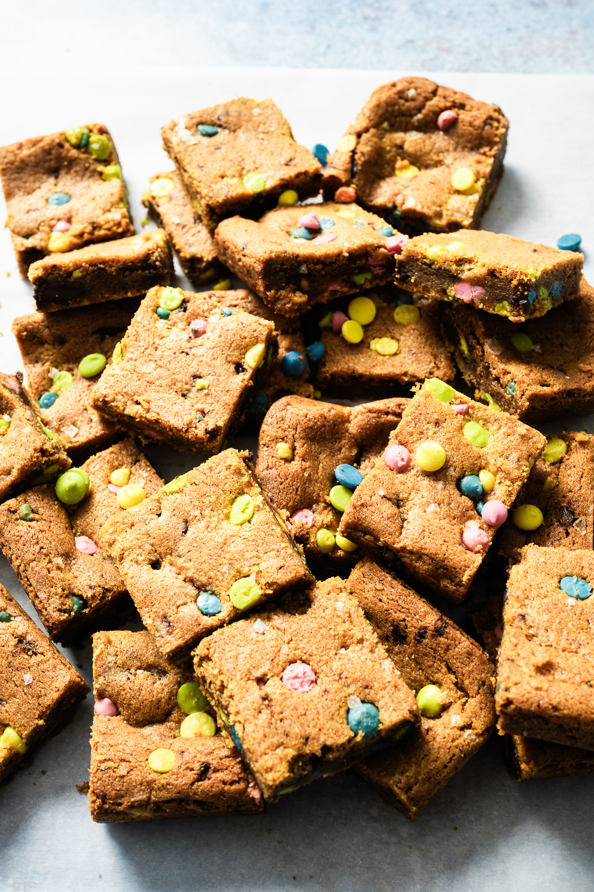 squares of chocolate chip cookie bars in a pile on parchment paper