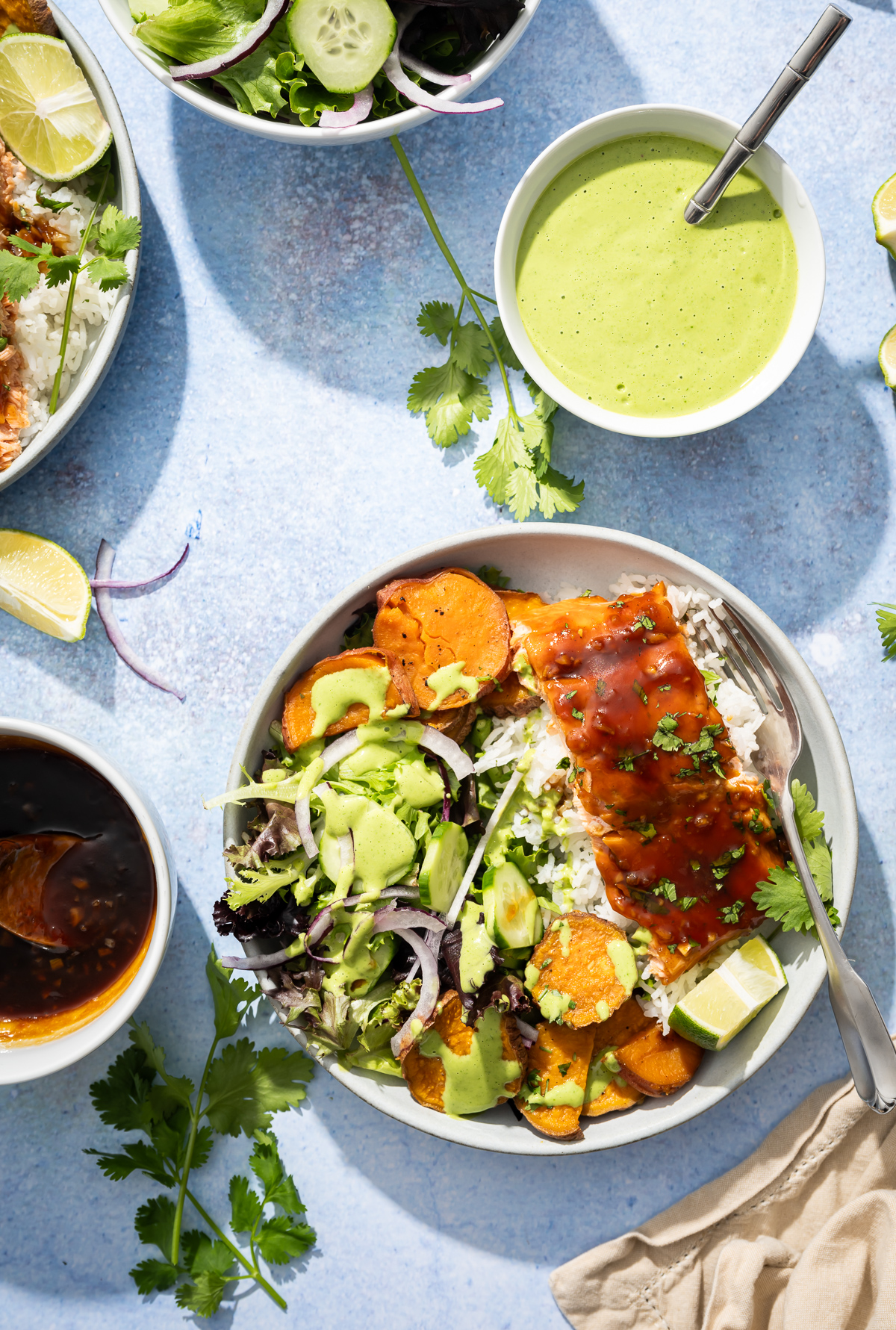 salmon fillets in bowls with sweet potato slices salad lime sliced bowl of green dressing bowl of hot honey sauce