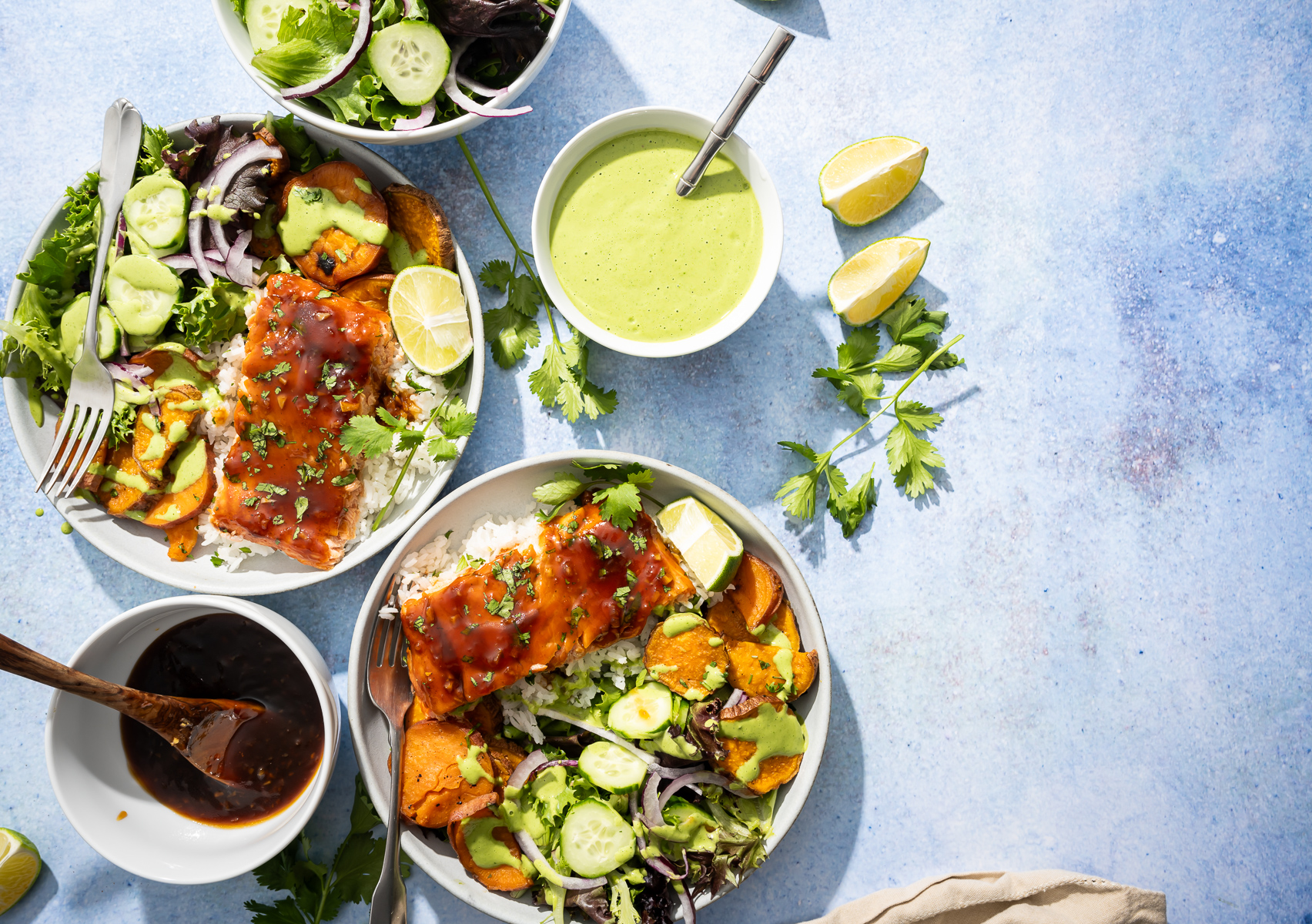 salmon fillets in bowls with sweet potato slices salad lime sliced bowl of green dressing bowl of hot honey sauce